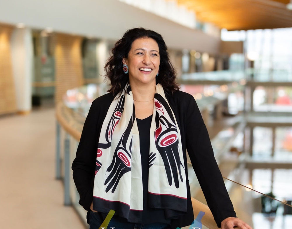 Alanaise Ferguson in a brightly lit atrium, wearing an Indigenous-designed scarf. 